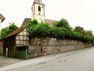 Ansicht von Nordosten mit Kirche (Kirchturm im Kern Frühgotisch) über Kirchhofmauer (Wehrgang mit Steinrüstung im 18 Jh abgetragen) von Ortsseite