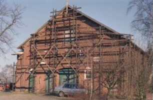 Langereihe 88: traufständiges Bauernhaus aus Backstein: Giebelseite Wirtschaftstrakt mit Scheunentor, Stalltüren, oben Luke: vor Fassade Gerüst