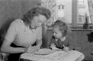 Reportage: Berliner Männer und Frauen tragen sich für die Ächtung der Atombomben ein : Mutter mit Kind trägt sich in die Unterschriftenliste ein