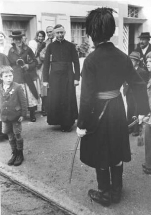 Schützenmeister in historischer Uniform steht vor einem Pfaffen stramm