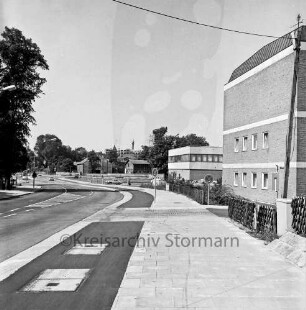 Oher Weg / Möllner Landstraße mit Pkws und Lkws: hinten links Einmündung: rechts Rathaus und Bürgerhaus Glinde [später Marcellin-Verbe-Haus]: dahinter Geschäftshaus am Markt: davor Lieferwagen: hinten Scheunen des ehemaligen Gutes Glinde: hinten links Turmspitze des Gutshauses zwischen Bäumen: im Hintergrund Wohnblock und Baukran