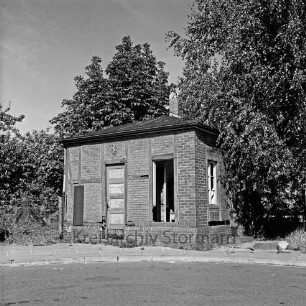 U-Bahnhof West: Toilettenhäuschen, geschlossen: ein Fenster herausgebrochen: Maschendrahtzaun, Bäume