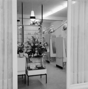 Salon Ute: Hamburger Straße: Friseursalon: Inhaberin Ute Subjetzki: Eröffnung: Innenaufnahme, Blick durch Fenster: Verkaufstheke, darauf Blumen: hinten rechts Kabinen mit Trockenhauben