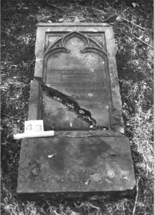 Grabstein 43 (Index: 100105904) Material: Sandstein Zustand: Stein liegend, quer gebrochen mit Textverlust Maße HxBxT: 133x60x17 cm Beschreibung: rechteckige Stele, Sockel, Schriftfeld eingetieft mit Spitzbogenabschluß Symbolik: Maßwerk: Grabstein 43