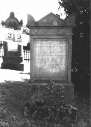 Grabstein 39 (Index: 100105203) Material: Sandstein Zustand: gut Maße HxBxT: 113x47x26 cm Beschreibung: Stele mit Podest, Sockel, Giebel mit Eckakroteren, Schriftfeld eingetieft: Grabstein 39