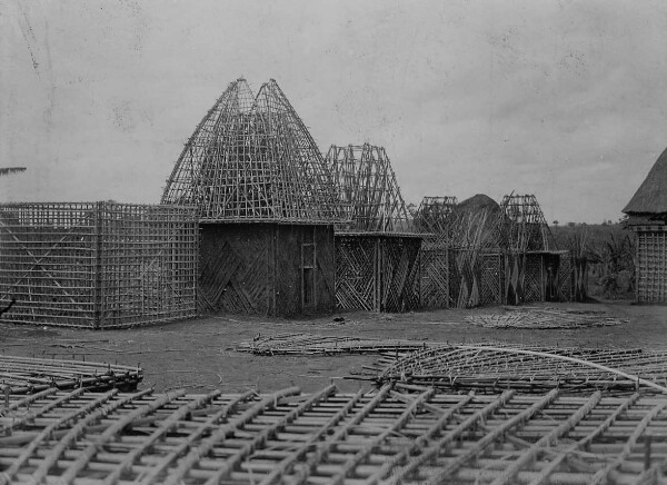 Several square huts under construction, various stages