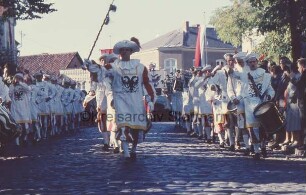 Reinfeld: Karpfenfest: Umzug: Paul-von-Schoenaich-Straße: Spielmannszug in Kostümen mit Tambourmajor: rechts und links Zuschauer: hinten Fahnenmasten, Häuser und Bäume: 11. Oktober 1959
