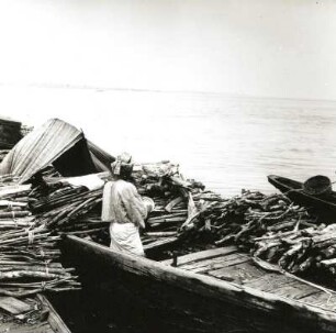 Lagos, Nigeria. Mit Holzbündeln beladene Boote am Strand