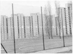 Durch das Gitter eines Sportplatzes auf eine Hochhaussiedlung fotografiert (Altersgruppe 14-17)