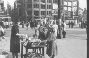 Berlin. Kinder begutachten Waren, die eine Frau auf einem Tisch ausgebreitet hat und zum Verkauf anbietet (Serie "Berliner Schnappschüsse")