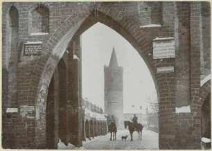 Jüterbog, Zinnaer Tor mit Ortstafel und Durchblick auf einen Bergfried, davor zwei Soldaten zu Pferd mit Hund