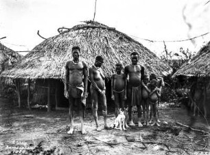 Indigene vor Rundhütten : Portrait einer Gruppe von Indigenen aus Ostafrika vor den Rundhütten einer Siedlung