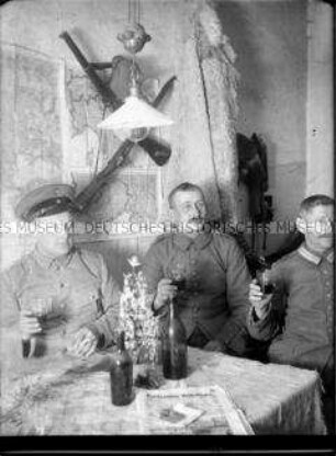 Soldaten an einem Tisch sitzend mit erhobenen Gläsern, 1. Weltkrieg