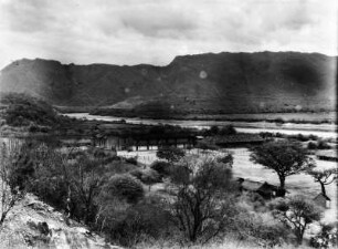 San Antonio-Villamontes mit Pilcomayo und Andenrand : Blick auf eine Siedlung mit Häusern. Im Hintergrund die Anden