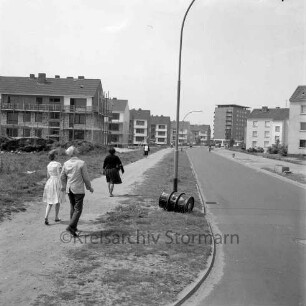 Stonsdorfer Weg: links Baustelle eines Wohngebäudes, dahinter und rechts weitere Wohngebäude, im Hintergrund das Rathausgebäude: Blick von Osten