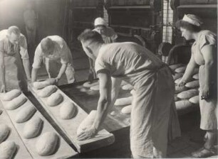 In einer Großbäckerei. Bäcker formen aus Teig Brotlaibe.