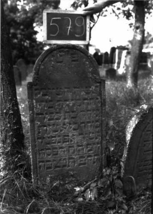 Grabstein 579 (Index: 100102471) Material: Sandstein Zustand: leicht verwittert Maße HxBxT: 90x42x8 cm Beschreibung: Stele, eingezogener Rundbogenabschluss, Schriftfeld eingetieft: Grabstein 579