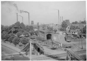 Frankenthal (Pfalz), Industriegebiet : Frankenthal (Pfalz). Industriegebiet mit Maschinenbau- und Armaturenfabriken sowie Kraftwerk. Im Vordergrund beschrankter Bahnübergang mit danebenliegender Fußgängerbrücke und Anschlußbahnanlagen mit Drehscheibe und Lokschuppen
