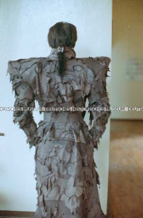 Modell (Sabine von Oettingen) in einem braunen Ledermantel mit Metallgürtel (Rückseite) der Designergruppe Allerleirauh