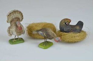 Figuren von drei Hühnervögeln: Truthahn, Pute und Huhn, beiliegend zwei Nester