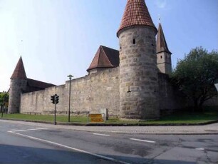 Ansicht von Nordosten mit Nordost-Rundturm (verschiedene Schießscharten) sowie Kirche über Kirchhofmauer und Südost-Rundturm