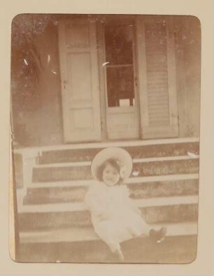 Christiane von Hofmannsthal als Kleinkind mit Hut auf Treppenstufen sitzend
