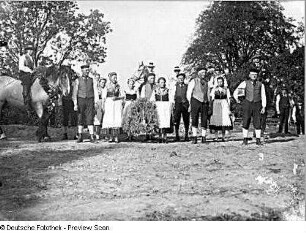 Fest der Landleute. Geschmücktes Pferd mit Reiter und Bauern, die auf Beginn des Festumzugs warten