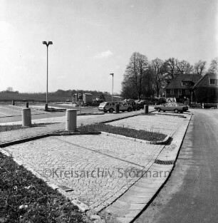 A 1: Raststätte "Trave" bei Reinfeld: Modernisierung: neue Parkplätze: Mülltonnen, Straßenlampen, parkende Autos, Personen, Verkehrsschilder, Bauwagen: hinten rechts Gaststättengebäude