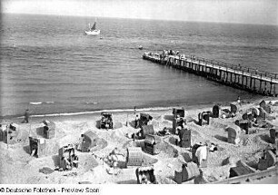 Blick über Ostseestrand mit Strandkörben und über Steg auf das Meer