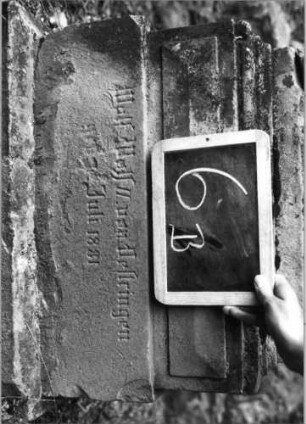 Grabstein 6 (Index: 100080725) Material: Sandstein, weiße Marmorplatte Zustand: Platte gesprungen, Aufsatz beschädigt Maße HxBxT: 165x49x27 cm Beschreibung: Stele, getreppter Sockel, Giebel mit Aufsatz, rechteckige Schriftplatte: Grabstein 6B