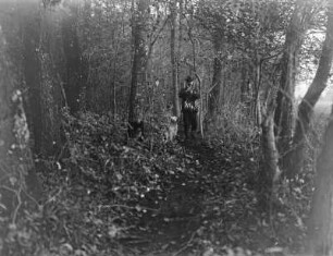 Vogelfänger mit Jagdbeute und Hund im Wald