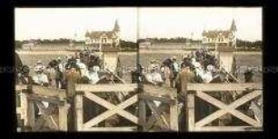 Blick von der Landungsbrücke mit Passagieren zum Kurhaus in Hela