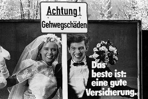Werbeplakat einer Versicherung mit einem Hochzeitspaar und Straßenschuld "Achtung! Gehwegschäden"