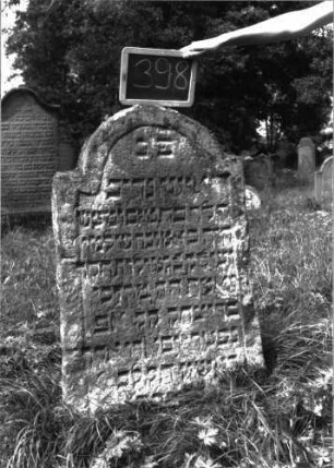 Grabstein 398 (Index: 100102827) Material: Sandstein Zustand: leicht verwittert Maße HxBxT: 113x63x10 cm Beschreibung: Stele, eingezogener Rundbogenabschluss, Schriftfeld eingetieft mit unregelmäßigen seitlichen Einzügen: Grabstein 398