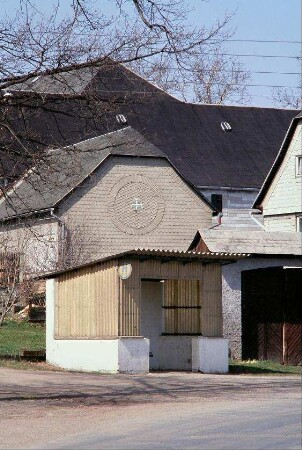 Bushaltestelle, dahinter Hof; ein Giebel mit Verzierung