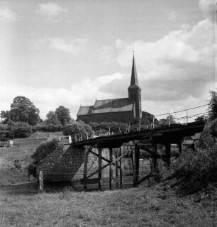 Trave: rechts Holzbrücke in baufälligem Zustand: vorn Wiese: hinten Kirchberg mit evangelischer Kirche