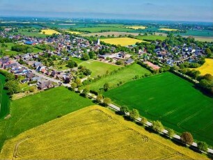 Steinburg: Luftbild des Ortsteils Mollhagen in Blickrichtung Norden, in der Umgebung blühende Rapsfelder, mittig Grundschule Mollhagen, im Vordergrund Sprenger Weg
