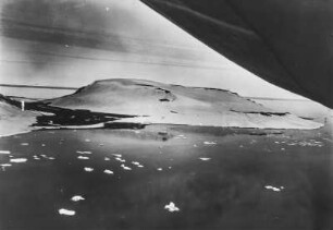 Vor der Hooker-Insel : Luftaufnahme der vergletscherten Hooker-Insel, die zu Franz-Josef-Land gehört. Vereinzelt Treibeis auf der Wasseroberfläche.