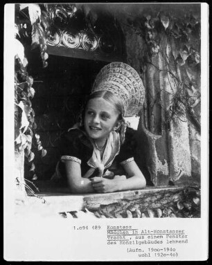 Mädchen in Alt-Konstanzer Tracht, aus einem Fenster des Konzilgebäudes lehnend