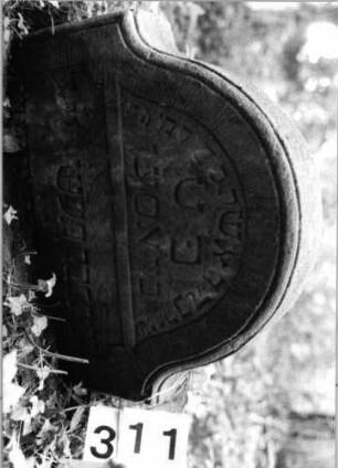 Grabstein 311 (Index: 99803478) Material: Sandstein Zustand: eingesunk(befestigt), Textverlust Maße HxBxT: 50x64x12 cm Beschreibung: Stele mit Karniesbogen und profiliertem Rand, Giebelfeld: Grabstein 311