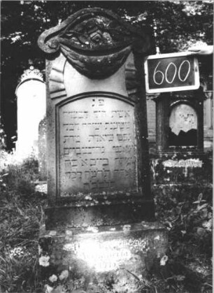Grabstein 600 (Index: 99895340) Material: Sandstein Zustand: gut, Sockel verwittert Maße HxBxT: 142x47x17 cm Beschreibung: Stele mit Konvexbogenabschluss; Sockel Symbolik: geknickte Rose, Girlande mit Bändern: Grabstein 600 (1)