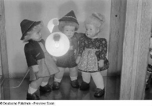 Puppen der Leipziger Herbstmesse 1954 in einer Vitrine, im Glas die Spiegelung des verwendeten Blitzgerätes