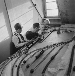 Eisenbahner in Uniform mit drei Kindern an einer Modellbahnanlage (Serie Deutsche Reichsbahn - Brigade "Otto Buchwitz")