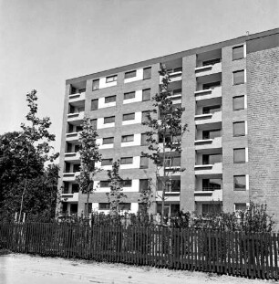Wohnblock nach Fertigstellung: davor Grünanlage mit Zaun