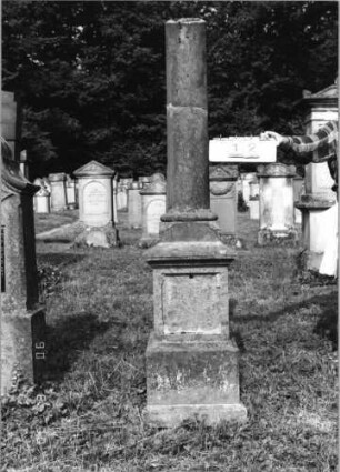 Grabstein 12 Material: Stein Zustand: hebräische Inschriftenplatte herausgebrochen, verwittert Maße HxBxT: 210x36x25 cm Beschreibung: Stele, Reihengrab, Schriftfeld eingetieft Symbolik: abgebrochene Säule Besonderheit: --: Grabstein 12