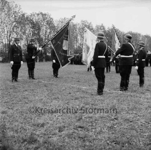 Meddewade: Freiwillige Feuerwehr Meddewade: Fahnenweihe: Festwiese: Fahnenträger mit der Meddewader Fahne und der Weihfahne des Amtes Bad Oldesloe-Land: dahinter Fahnenträger benachbarter Wehren: hinten angetretene Wehren und Zuschauer: 01.06.1974