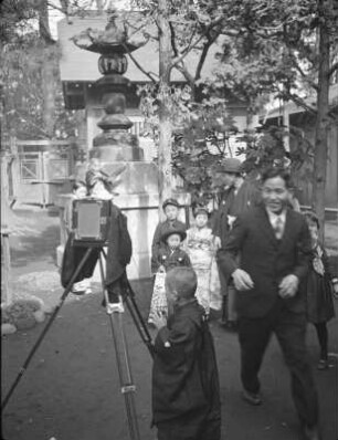 Kashima-Schrein, wahrscheinlich in Shinagawa, während des Shichi-go-san-Festes im November : Kashima-Schrein, wahrscheinlich in Shinagawa, während des Shichi-go-san-Festes im November. Ansicht mit Steinlaterne, Plattenkamera und Besuchern