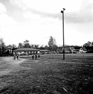 Sporteinrichtungen: Sportanlage am Kortenkamp: rechts Beleuchtungsmast: links Gruppe Schulkinder: dahinter Sportlerheim: Sportverein (SV) Großhansdorf von 1942 e. V.: hinten rechts Häuser: dahinter Bäume