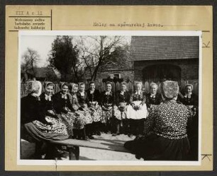 Mädchen in Schleifer Tracht aus Rohne auf der Singebank in Rohne. : Holcy w Slepjanskej drasće z Rowneho na spěwarskej ławcy w Rownom.