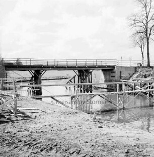Trave: Brückenneubau: Notsteg, dahinter alte Holzbrücke: rechts Baum